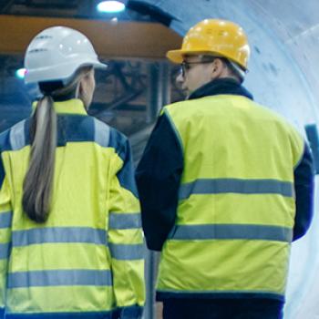 three workers with hard hats on in industrial plant